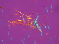 numerous multi-colored needle-shaped crystals against a purple background